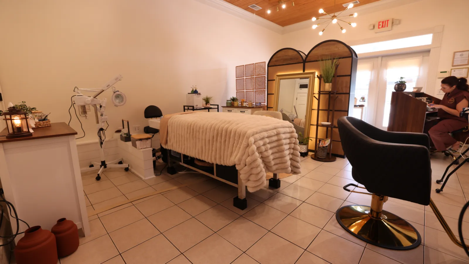 Private head spa room with a treatment bed under a cream blanket, a steamer and lamp stand, a styling chair and a desk by the windows